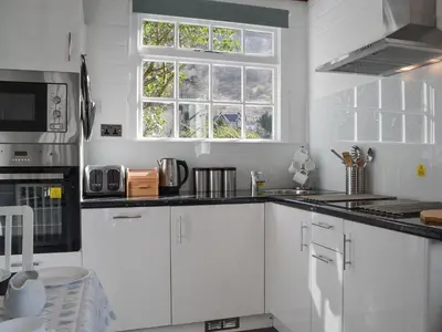 a white kitchen with white cabinets and a window at Field House Lodge in Borrowdale Valley