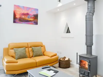 a living room with a couch and a wood stove at Ramerish Retreat in Laurieston