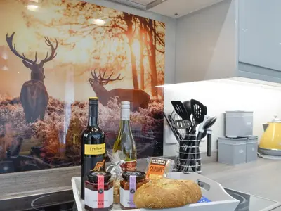 a kitchen counter with wine bottles and a loaf of bread at Ramerish Retreat in Laurieston