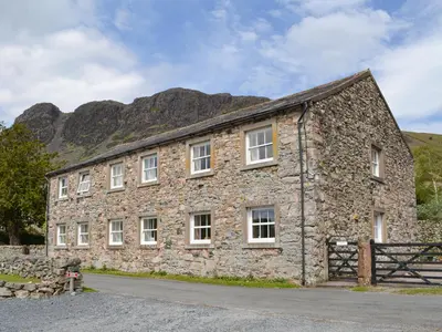an old stone building with mountains in the background at The Retreat in Nether Wasdale