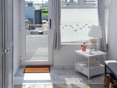 a room with a door and a table and a window at Honeysuckle Cottage in Springside