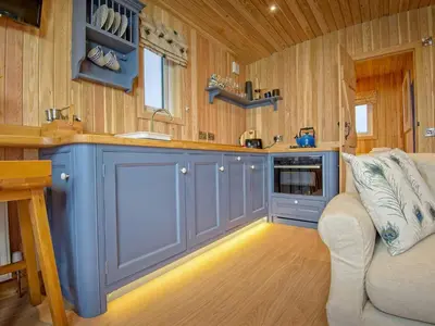 a kitchen with blue cabinets and a couch in a room at Little Oak - Uk5996 in Carsluith