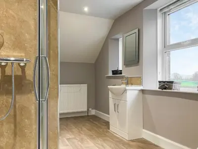 a bathroom with a shower and a sink and a window at Halleaths Home Farm in Lochmaben
