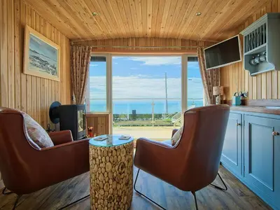 a living room with chairs and a large window at Little Beach - Uk5997 in Carsluith