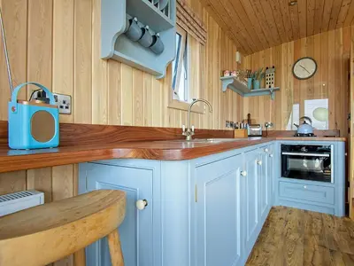 a kitchen with blue cabinets and a wooden wall at Little Beach - Uk5997 in Carsluith