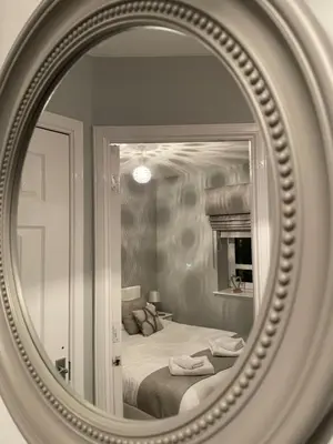 a mirror reflecting a bedroom with a bed in it at No 7 Ayr Beach - Coorie Doon in Ayr