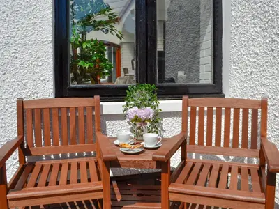 two wooden chairs and a table with cups and flowers at Blair Terrace in Portpatrick