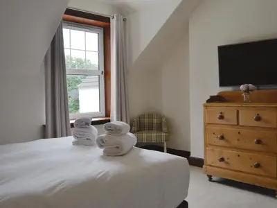 two towels on a bed in a bedroom with a television at Blair Terrace in Portpatrick