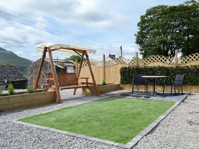 a garden with a table and an umbrella at The Rocking Lodge in Threlkeld