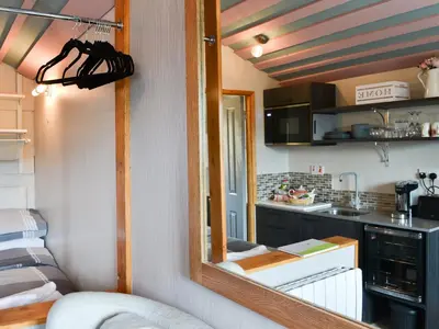 a room with a mirror and a kitchen with a counter at The Rocking Lodge in Threlkeld