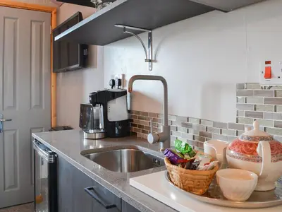 a kitchen counter with a sink and a basket of food at The Rocking Lodge in Threlkeld