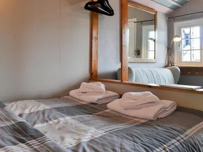 a bedroom with two towels on a bed in front of a mirror at The Rocking Lodge in Threlkeld