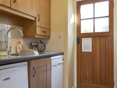 a kitchen with wooden cabinets and a sink and a door at Causey View in Keswick