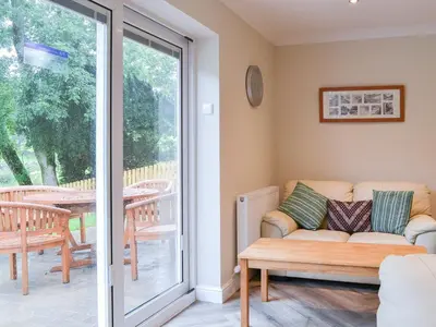 a living room with a couch and a sliding glass door at Lucy's At The Grange - Uk11519 in Mockerkin