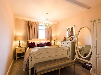 a bedroom with a bed with a mirror and a chair at Woodend in Maxwelltown