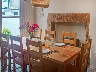 a dining room with a wooden table and a fireplace at Wanderers Rest in Keswick