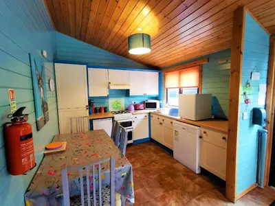 a kitchen with a table and a kitchen with blue walls at Glen Bay - 2 Bed Lodge on Friendly Farm Stay with Private Hot Tub in New Cumnock
