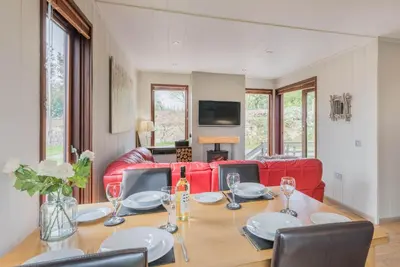 a dining room with a table and a red couch at Dobby Lodge in Bassenthwaite