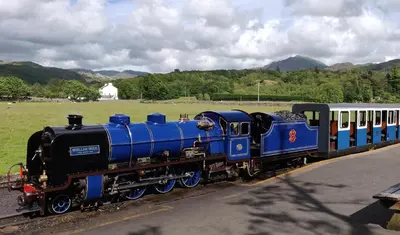 a blue train on a track next to a field at Row Farm Cottage in Millom