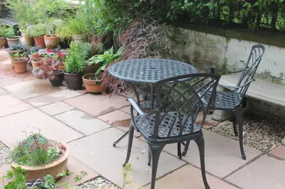 two chairs and a table in a garden with potted plants at Number 48 in Dumfries