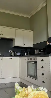 a kitchen with white cabinets and a stove top oven at Dovenby Apartment- great base for exploring Lake District in Cockermouth
