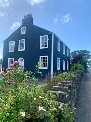 a blue house with flowers in front of it at Dovenby Apartment- great base for exploring Lake District in Cockermouth