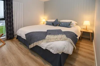 a bedroom with a large white bed with blue pillows at The Salt Lodge in Troon
