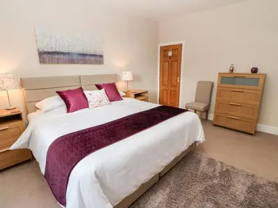 a bedroom with a large bed with purple pillows at Berrymoor Cottage in Brampton
