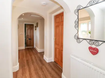 a hallway with a door and a heart ornament on the wall at Berrymoor Cottage in Brampton