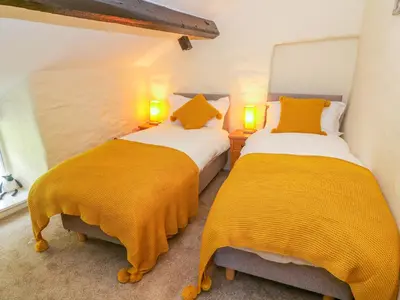 two beds in a room with yellow blankets at Tilberthwaite Farm Cottage in Coniston