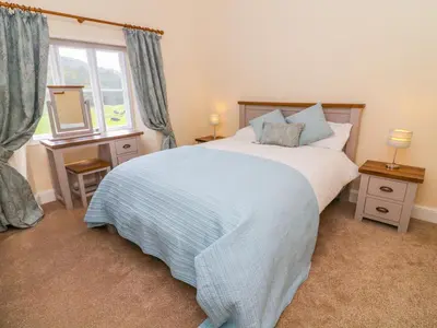 a bedroom with a large bed and a window at Tilberthwaite Farm Cottage in Coniston