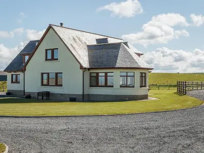 a white house with a black roof on a field at Corsewall Castle Farm Lodges in Stranraer