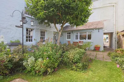 a white house with a tree in the yard at 57 High Street in Kirkcudbright