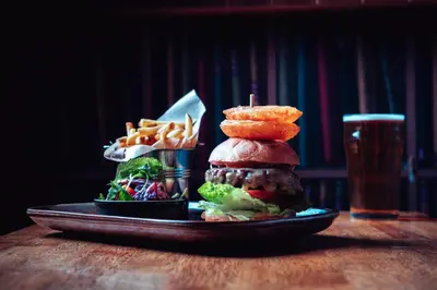 a plate with a sandwich and french fries and a glass of beer at The White Horse Inn Bunkhouse in Threlkeld