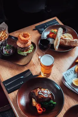 a wooden table topped with plates of food and drinks at The White Horse Inn Bunkhouse in Threlkeld