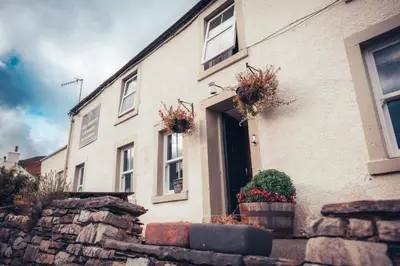a white brick house with flower pots on the door at The White Horse Inn Bunkhouse in Threlkeld