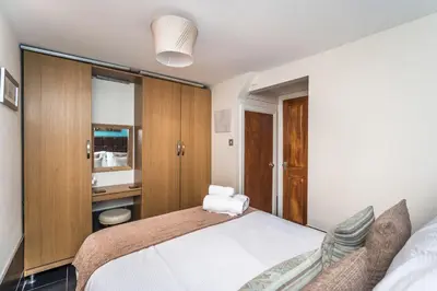 a bedroom with a white bed and a chair at Tithe Cottage in Keswick