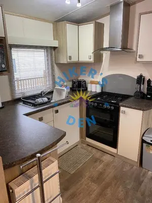 a kitchen with white cabinets and a stove top oven at Hikers Den, Brigham, Cockermouth, Cumbria in Cockermouth