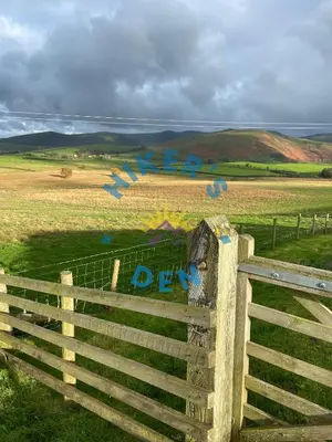 a fence with graffiti on it in a field at Hikers Den, Brigham, Cockermouth, Cumbria in Cockermouth