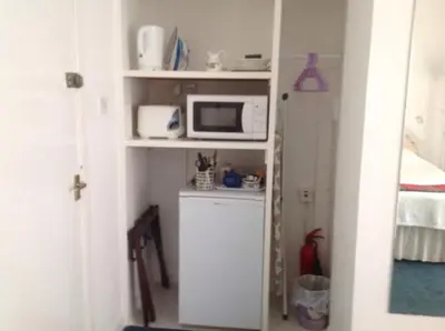 a small kitchen with a microwave on a shelf at The Clan MacGregor Room in Kilmarnock