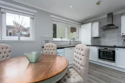 a kitchen with a wooden table and white cabinets at Iona Residence - Donnini Apartments in Ayr