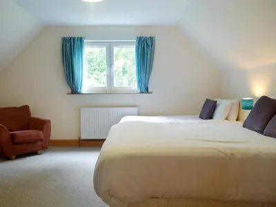 a bedroom with a bed and a window and a chair at Cressfield Villa in Ecclefechan