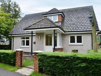 a small white house with a black roof at Cressfield Villa in Ecclefechan