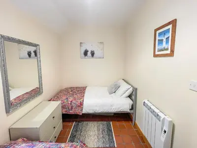 a small bedroom with a bed and a mirror at The Smiddy in Glasserton