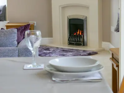 a table with a plate and a wine glass and a fireplace at Easedale Corner in Grasmere