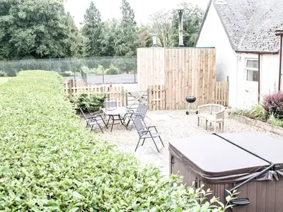 a backyard with chairs and tables and a fence at The Brewers Cottage in Mauchline