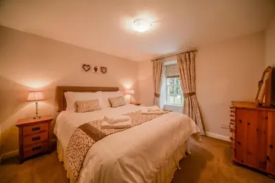 a bedroom with a large bed and a window at Blairquhan Cottages in Maybole