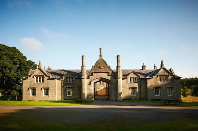 an old stone house with an arch entrance at Blairquhan Cottages in Maybole