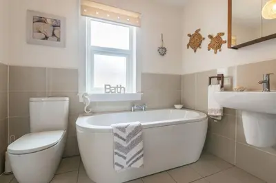 a bathroom with a tub and a toilet and a sink at Arran View in Prestwick