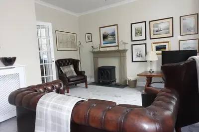 a living room with leather furniture and a fireplace at Providence Cottage in Kirkcudbright
